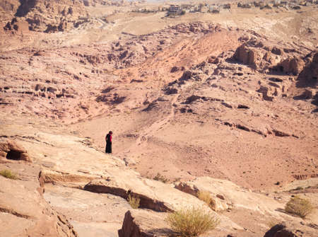 Alone bedouin woman or man in the deserted city of Petra, Jordan and Wadi Musa city , in the backgroundの写真素材