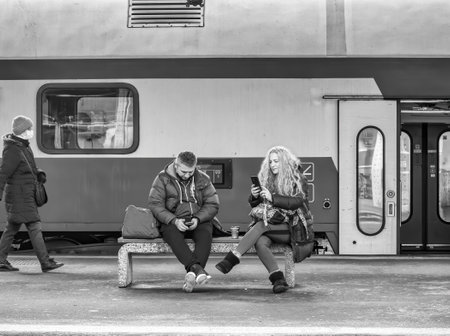 Bucharest, Romania - 01.01.2022: Two people sitting on a bench and waiting the train at the North Railway station in Bucharest.のeditorial素材