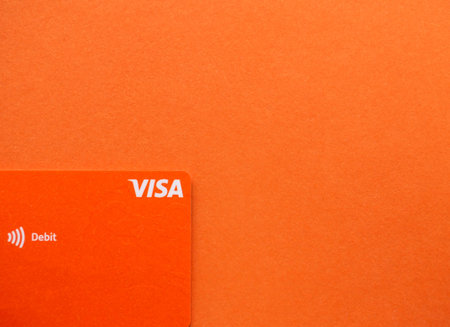 Bucharest, Romania - 03.25.2022: Orange Visa credit or debit card on gradient background. Online electronic commerce conceptのeditorial素材