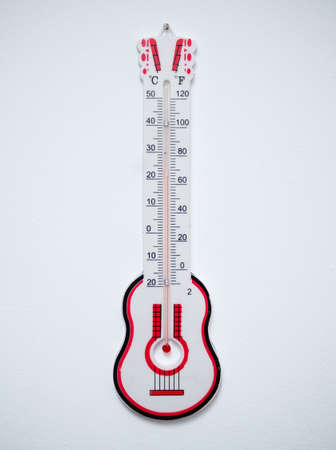 Thermometer in the shape of a guitar on a white wallの写真素材