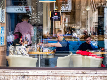 Bucharest, Romania - 04.08.2022: Tourist asian family at a restaurant coffee shop in the center of...