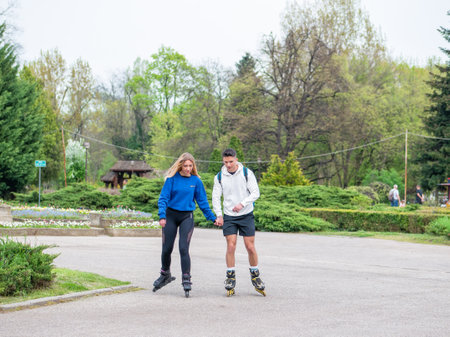 Bucharest, Romania - 04.15.2022: Couple on rollerblades holding hands enjoying a beautiful day in King Mihai I park (Herestrau)のeditorial素材