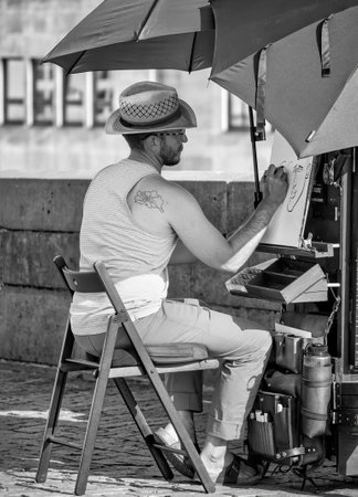 Prague, Czech Republic - June 2022:Street artist on Charles bridge making a sketch or a portrait. Black and white street photographyのeditorial素材