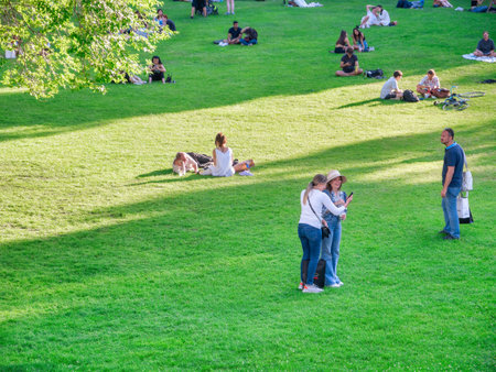 Vienna, Austria - June 2022: People, tourists and locals relaxing and having fun on the green grass in Burggarten park in Vienna.のeditorial素材