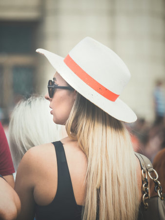 Rear view with a blonde hair woman with a white sun hat on her head.