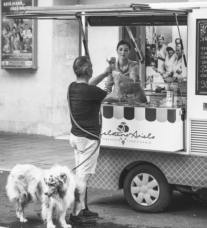 Bucharest, Romania - August 2022: Man with a dog pet buying ice cream from a mobile truck street vendor in the center of Bucharest.のeditorial素材