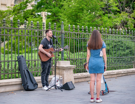 Bucharest, Romania - August 2022: Young street artist with a acoustic guitar playing in the center of Bucharest (Victory street - Calea Victoriei).のeditorial素材