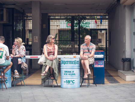 Bucharest, Romania - August 2022: Urban scene with middle age couple sitting at a table and having a beer drink in the old town center of Buchares.のeditorial素材