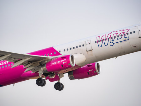 Bucharest, Romania - August 2022: A Wizz Air Airbus A321 airplane flying against blue cloudy sky from Henri Coanda International Airport.のeditorial素材