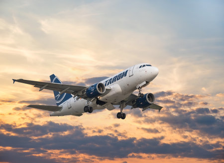 Bucharest, Romania - August 2022: TAROM Airbus A318 airplane flying against the sky at sunset. Airplane takes off from Henri Coanda International Airport.のeditorial素材