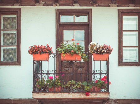 Picture with a beautiful rustic house. Front view of a balcony with flower pots in Veliko Tarnovo, Bugaria.の写真素材