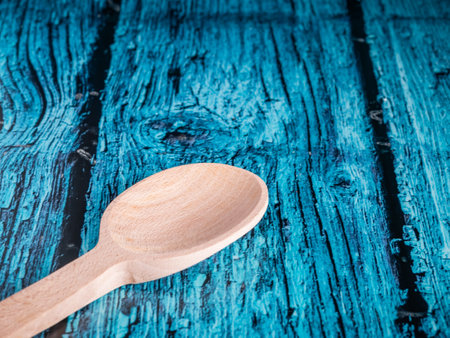 A hand made craft wooden spoon in the kitchen. Isolated spoon on blue background.の写真素材