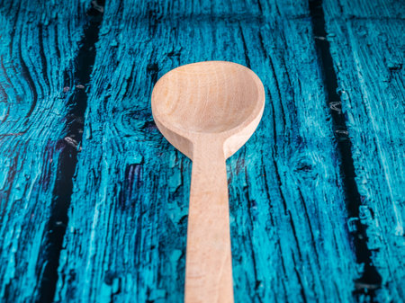 A hand made craft wooden spoon in the kitchen. Isolated spoon on blue background.の写真素材