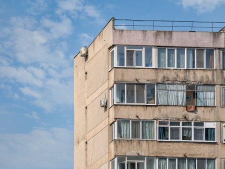 Worn out apartment building from the communist era against blue sky in Bucharest Romania. Ugly traditional communist housing ensembleの写真素材