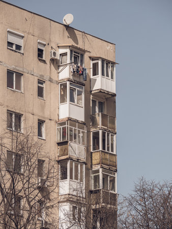Worn out apartment building from the communist era against blue sky in Bucharest Romania. Ugly traditional communist housing ensembleの写真素材