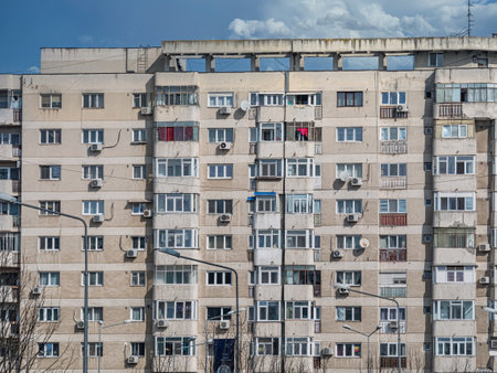 Worn out apartment building from the communist era against blue sky in Bucharest Romania. Ugly traditional communist housing ensembleの写真素材