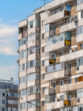 Worn out apartment building from the communist era against blue sky in Bucharest Romania. Ugly traditional communist housing ensembleの写真素材