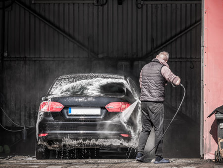 Unidentified man washing a car at a car wash.の写真素材