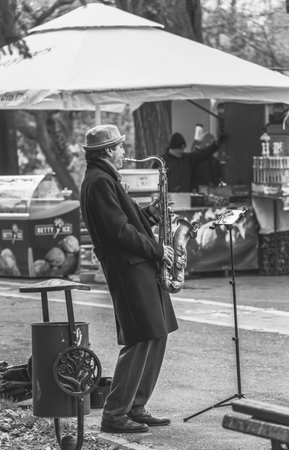 Bucharest, Romania - April 2023: Street musician man playing at saxophone in King Mihai I park ( Herestrau), in Bucharest.のeditorial素材