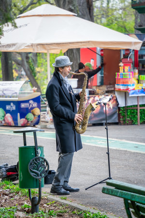 Bucharest, Romania - April 2023: Street musician man playing at saxophone in King Mihai I park ( Herestrau), in Bucharest.のeditorial素材