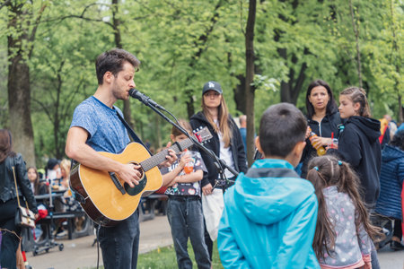 Bucharest, Romania - August 2022: Young street artist with a acoustic guitar playing in the center of Bucharest (Victory street - Calea Victoriei).のeditorial素材