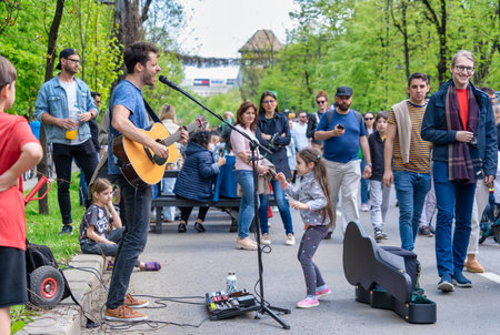 Bucharest, Romania - August 2022: Young street artist with a acoustic guitar playing in the center of Bucharest (Victory street - Calea Victoriei).のeditorial素材