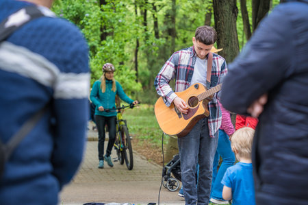 Bucharest, Romania - August 2022: Young street artist with a acoustic guitar playing in the center of Bucharest (Victory street - Calea Victoriei).のeditorial素材