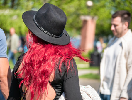 Rear view with a unidentified red head woman wearing a black hat. Attractive woman in the parkの写真素材