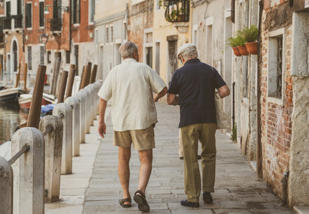 Two italian senior men walking on the cobblestone narrow streets in Venice, Italyの写真素材