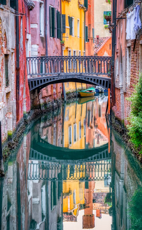 Narrow water canal and red brick worn out buidings built on water in Venice, Italy.の写真素材