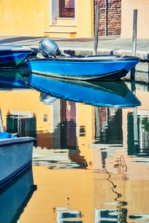 Picturesque colorful idyllic scene with a boats docked on the water canals in Burano Venice Italy. Water reflection.の写真素材