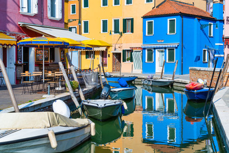 Picturesque colorful idyllic scene with a boats docked on the water canals in Burano Venice Italy. Water reflection.の写真素材