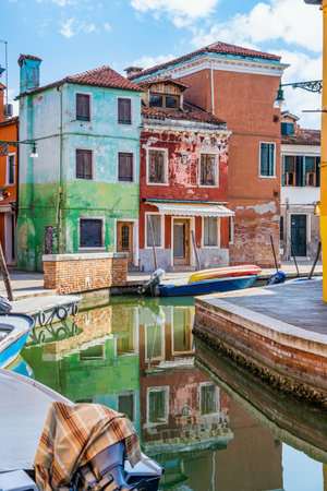 Picturesque colorful idyllic scene with a boats docked on the water canals in Burano Venice Italy. Water reflection.の写真素材