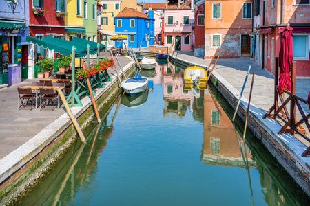 Picturesque colorful idyllic scene with a boats docked on the water canals in Burano Venice Italy. Water reflection.の写真素材
