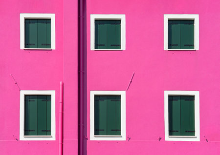 Detail with a pink colorful house window with green painted wooden shutters in Burano, Italy.の写真素材