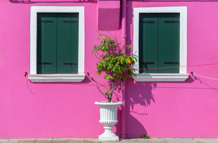 Detail with a pink colorful house window with green painted wooden shutters in Burano, Italy.の写真素材
