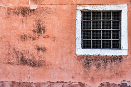 Old red brick wall with two rusted iron grill windows.の写真素材