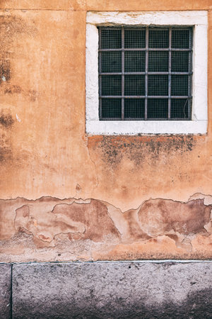 Old red brick wall with two rusted iron grill windows.の写真素材