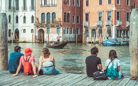 Venice, Italy - May 30 2023: Tourists sitting on a wooden boat pier and enjoying the idyllic scene on Grand Canal in Venice.のeditorial素材
