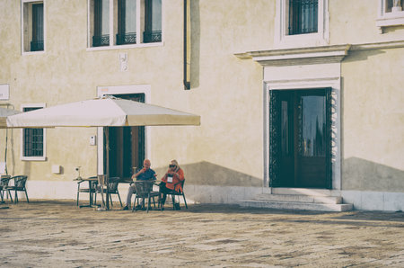 Venice, Italy - May 30 2023: Senior tourist couple at an outdoor restaurant cafe in Venice.. Picturesque idyllic sceneのeditorial素材