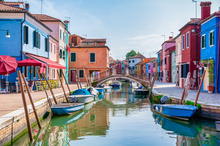 Picturesque colorful idyllic scene with a boats docked on the water canals in Burano Venice Italy. Water reflection.のeditorial素材