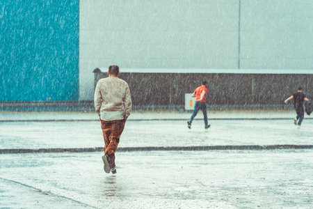 Three men in the heavy rain running for cover.の写真素材