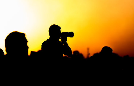 A silhouette of a photographer with a camera at sunset.