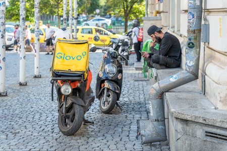 Bucharest, Romania - August 17 2023: Glovo food delivery courier checking his phone for orders in the old town center of Bucharest.のeditorial素材