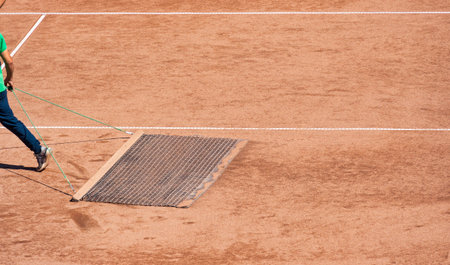 A man clean sweeping the tennis court clay surface.の写真素材