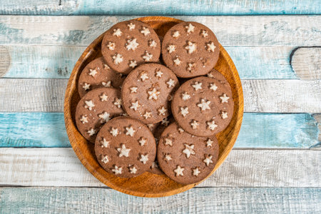 Delicious sweet cocoa cookies biscuits on a wooden plate . Overhead shot. Colorful blue background.の写真素材