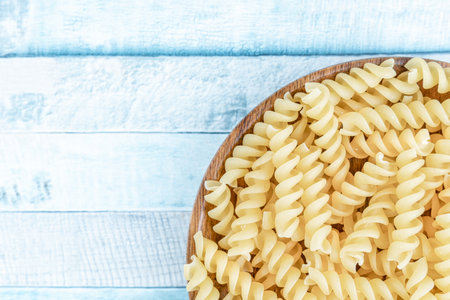 Raw italian fusilli spiral pasta on a wooden plate. Close up detail food photography.の写真素材