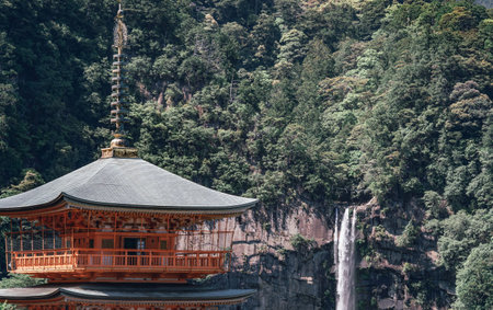 The red three-story pagoda of Seigantoji Buddhist Temple in front of Nachi Falls. Beautiful natural...