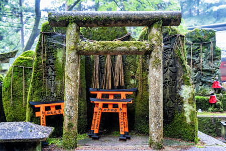 Small shinto place of worship with Torii Gates and inscriptioned stones at Fushimi Inari Taisha temple in Kyoto, Japan. ( Japanese inscriptions translated are different religion blessings)の写真素材