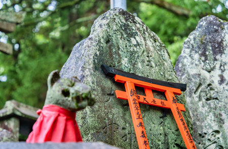 Small shinto place of worship with Torii Gates and inscriptioned stones at Fushimi Inari Taisha temple in Kyoto, Japan. ( Japanese inscriptions translated are different religion blessings)の写真素材